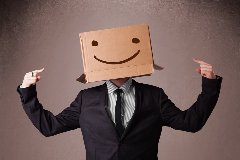 Businessman standing and gesturing with a cardboard box on his head with smiley face