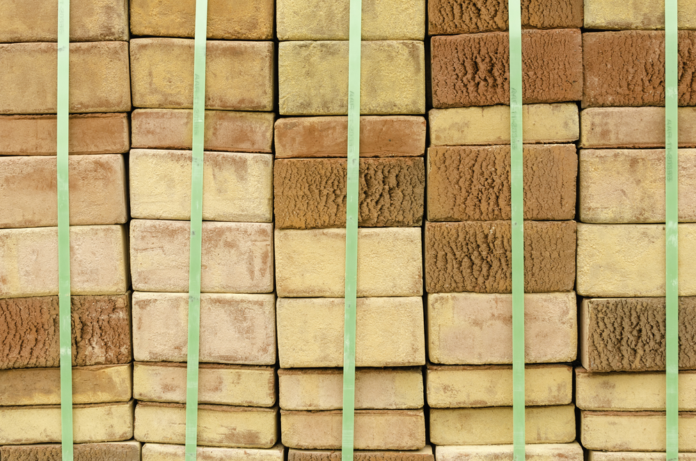 Geometric arrival of spring Stacks of beige bricks delivered for landscaping in botanical garden, for themes of order, balance, permanence, proportion